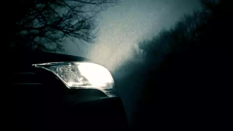 A car turned on its headlights in the darkness.